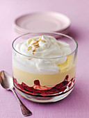 Classic british trifle in glass bowl made from raspberries sponge custard and cream topped with roasted almonds
