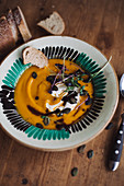 Pumpkin soup with pumpkin seeds, sour cream, cress and pumpkin seed oil