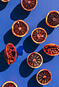 Halved blood oranges throwing a shadow on a blue background
