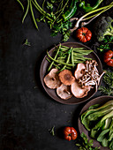 Composed wooden bowls with various healthy green and mushroom on black table