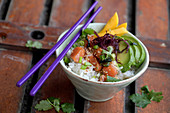 A poke bowl with raw marinated salmon, avocado and rice