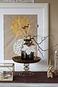 Dried flowers in vase, poppy seed heads and origami leaves