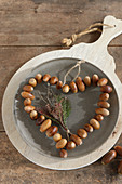 Heart of threaded acorns on plate on board