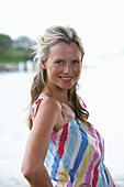 A young blonde woman on a beach wearing a light-blue top