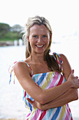 A young blonde woman on a beach wearing a light-blue top