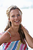 A young blonde woman on a beach wearing a light-blue top