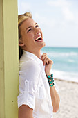 A young blonde woman on a beach wearing a white blouse