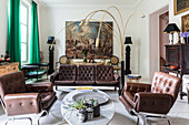 Brown leather sofa set and Italian designer lamp in living room with huge painting in background