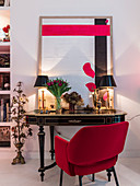 Roter Polsterstuhl am Antik Tisch mit Tischleuchten und moderner Kunst