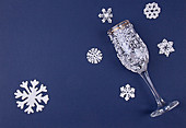 Deko-Schneeflocken aus Zuckerguss und Weinglas mit Zuckerguss auf blauem Untergrund