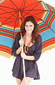 A brunette woman wearing a purple bath robe with a colourful parasol