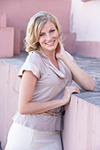 A blonde woman wearing a light blouse and a white skirt