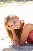 A young blonde woman on a beach wearing a pink top