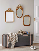 Three gold-framed mirrors above an upholstered bench with storage