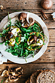 Two bruschette with olive oil ruccola and mushrooms on a wooden plate