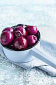 Peeled purple onion in blue saucepan