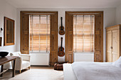 Gitarren an der Wand in weißem Schlafzimmers mit Fensterläden aus Kiefernholz