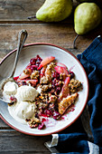 Cranberry pear crisp with ice cream on a wooden background