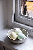 Eier in Schüssel vor altem Fenster