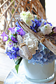 Treibhölzer und blau-weiße Blüten arrangiert zu sommerlichem Blumenschmuck