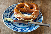 A buttered pretzel with a knife on a blue-and-white plate