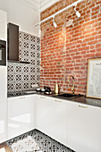 Küche in kleinem Appartment mit Ziegelsteinwand und schwarz-weißen Wand- und Bodenfliesen