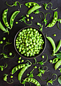 Shelled green peas and pea pods on a black background