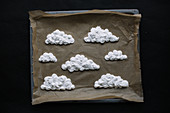 Unbaked meringue clouds on a baking tray lined with baking paper