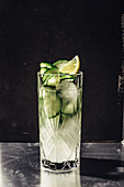 Cucumber gin with tonic in a crystal glass against a dark background