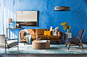 Braune Ledercouch, Sessel und Couchtisch im Wohnzimmer mit blauer Wand