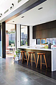 Kitchen island with bar stools in front of a patio door in an elegant kitchen in an open space