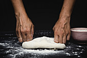 Woman's hands kneading bread on kitchen table