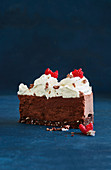 A slice of chocolate mousse cake with coconut, cream and raspberries