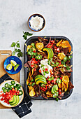 Baked nachos with chili con carne, avocado, coriander and sliced chillies