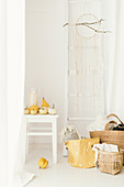 Pale, modern, autumn arrangement of pumpkins, ladder on wall, dreamcatcher and baskets