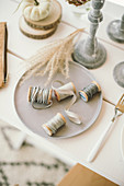 Autumnal arrangement of reels of string and ribbon, pumpkins, wooden discs and candlesticks on table