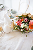 Colourful spring bouquet wrapped in paper on table set for Easter