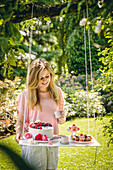 Woman stood next to cakes on DIY suspended table in garden