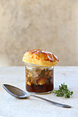 Mushroom broth with a puff pastry topping in a glass