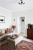 Upholstered sofa and matching upholstered table in beige on kilim