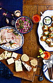 A Christmas buffet with ham, coleslaw, baked potatoes, cheese and crackers