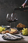 Vorspeisenplatte mit Crackern, Käse, Trauben und Nüssen serviert mit Rotwein