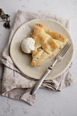 A slice of an apple pie, served with a scoop of vanilla ice-cream