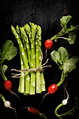 A bundle of green asparagus and radishes