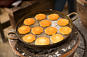 Many egg cakes in a brass pan on an ancient charcoal stove, Samut Songhkram, Thailand
