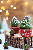 Weihnachtliche Schokoladenmuffins mit grüner Cremehaube auf Baumscheibe