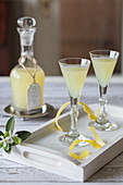 Limoncello in a carafe and two glasses on a wooden tray