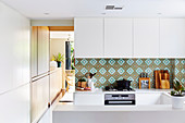 White fitted kitchen with colored tiles as splash protection