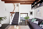 Gray upholstered sofa in the living room with beamed ceilings and stairs