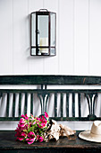 Antique brass and glass wall lantern over wooden bench with gloriosa